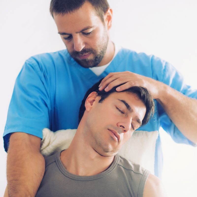 Physiotherapist doing healing treatment on man's neck, Therapist wearing blue uniform, Osteopath,  Chiropractic adjustment,