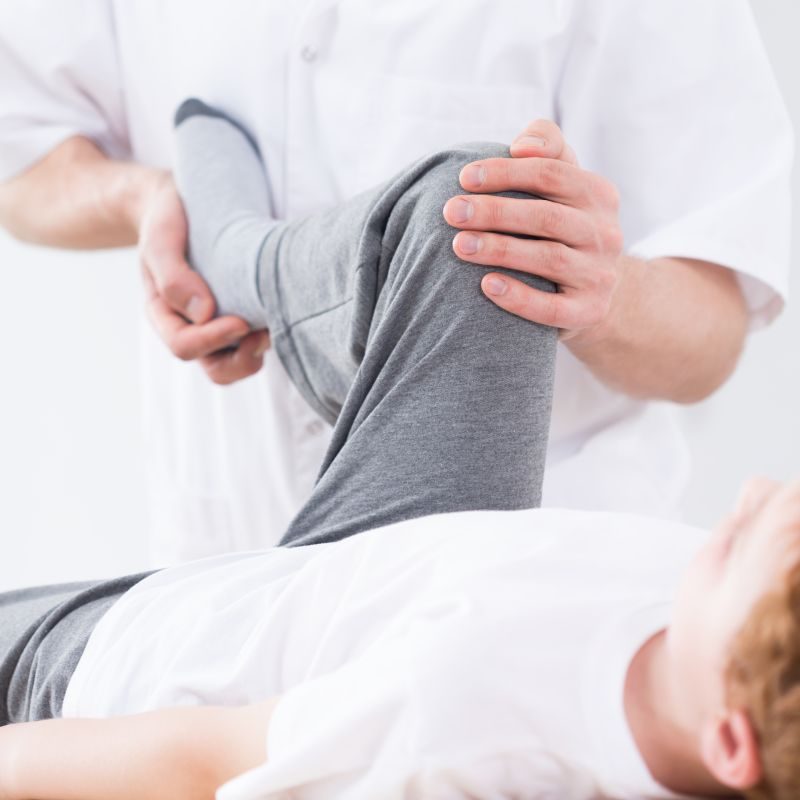 Physiotherapist doing passive exercise after boy's leg injury