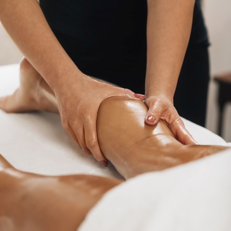 Anti cellulite massage. Masseuse massaging a calf area of a female leg to reduce cellulite